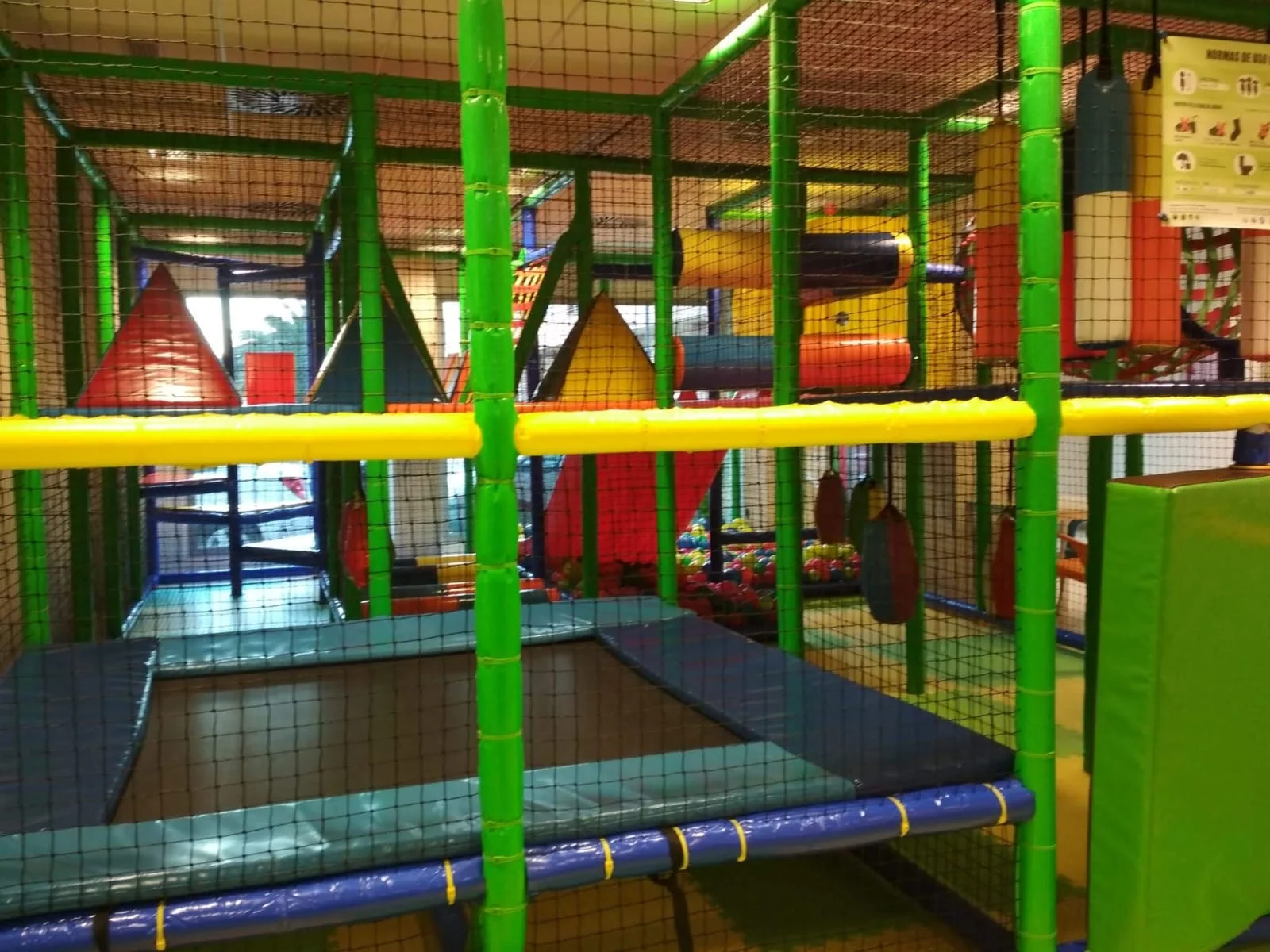 Cama elástica en parque infantil con estructura de seguridad